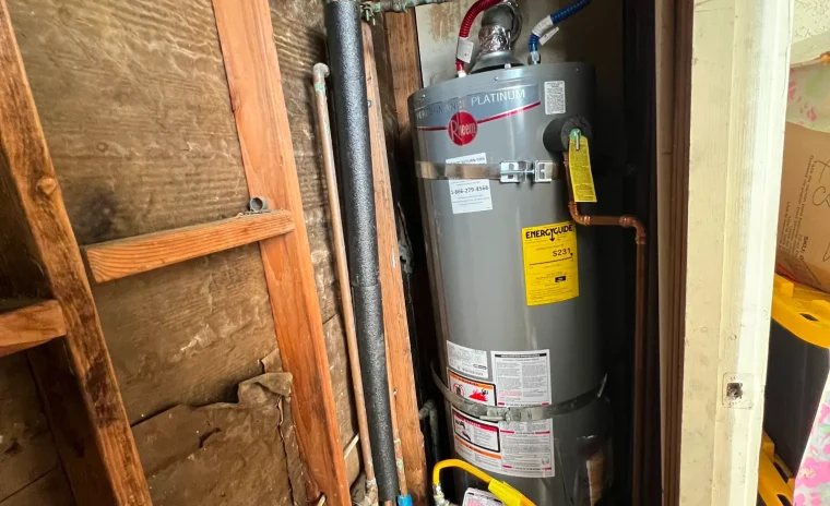 A gray Rheem water heater installed with connected pipes inside a narrow closet space.